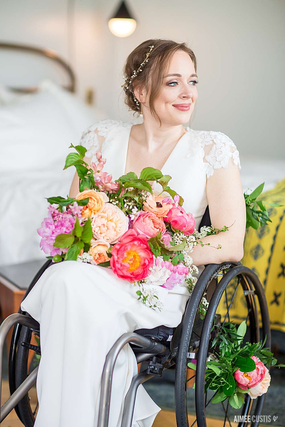 Beth sitting in her wheelchair wearing a wedding dress and holding a large bouquet of flowers.